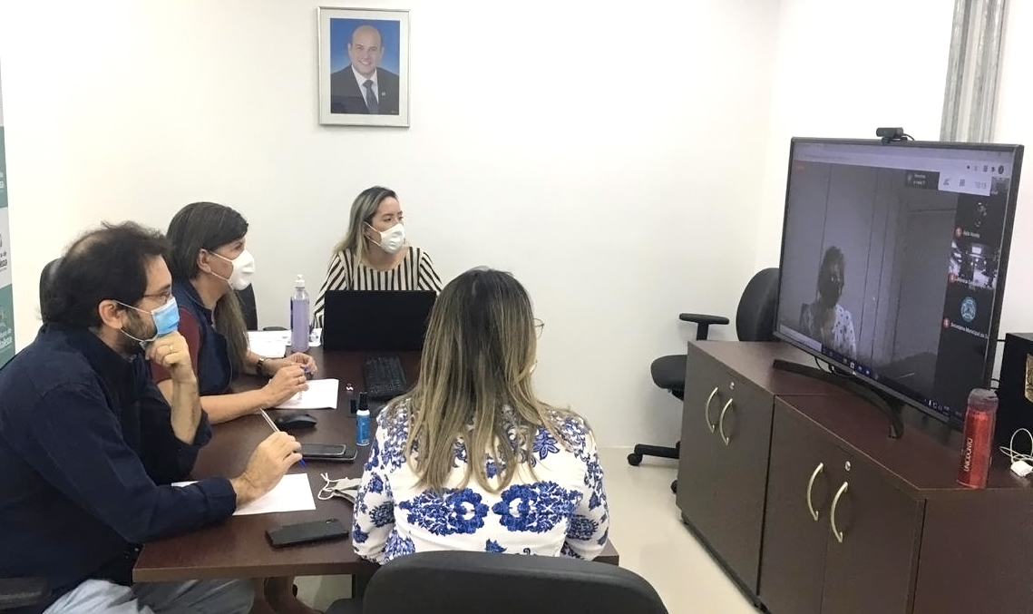 pessoas sentadas ao redor de mesa olhando para telão